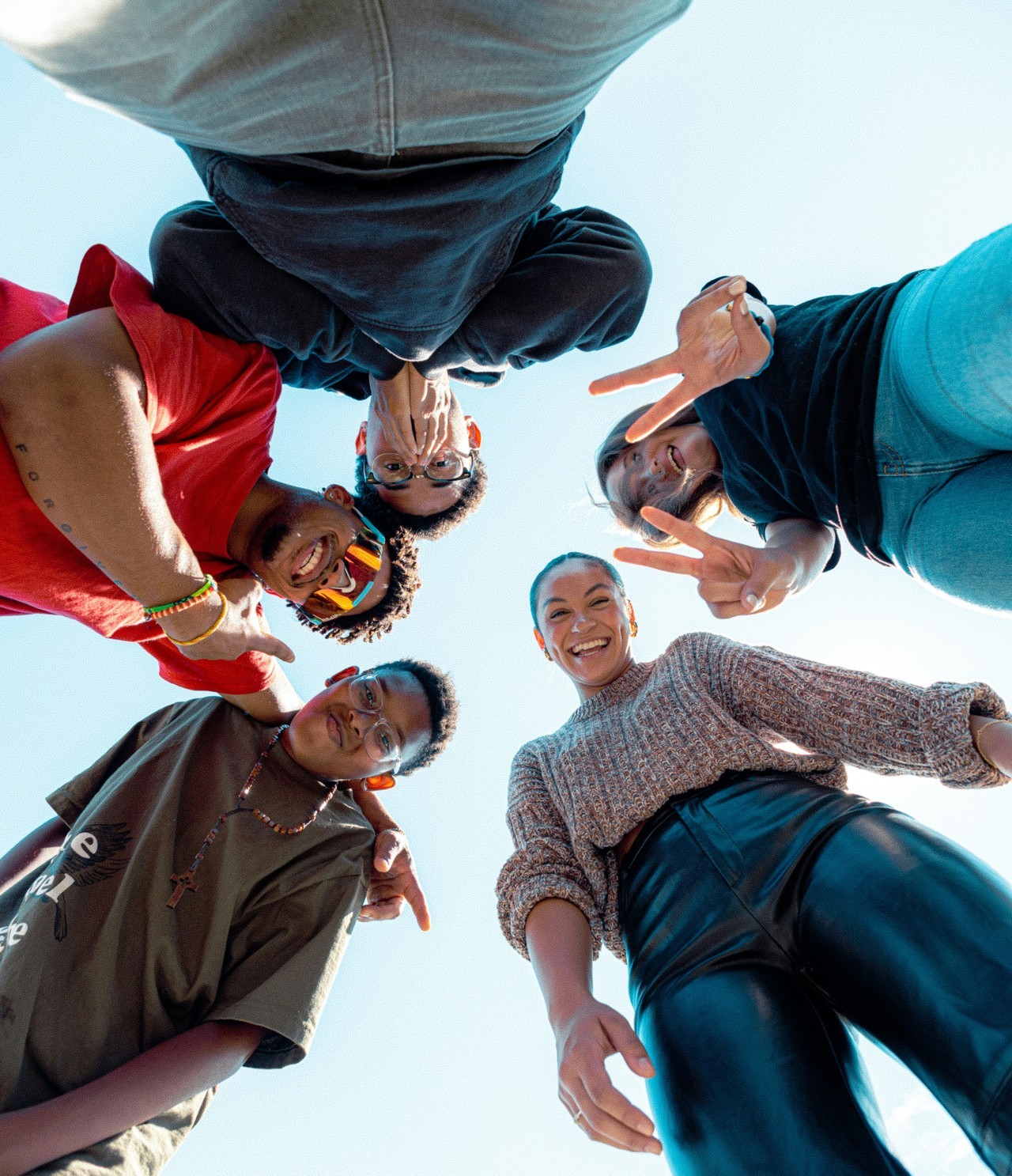 A group of joyful young people smiling together, huddled in a circle